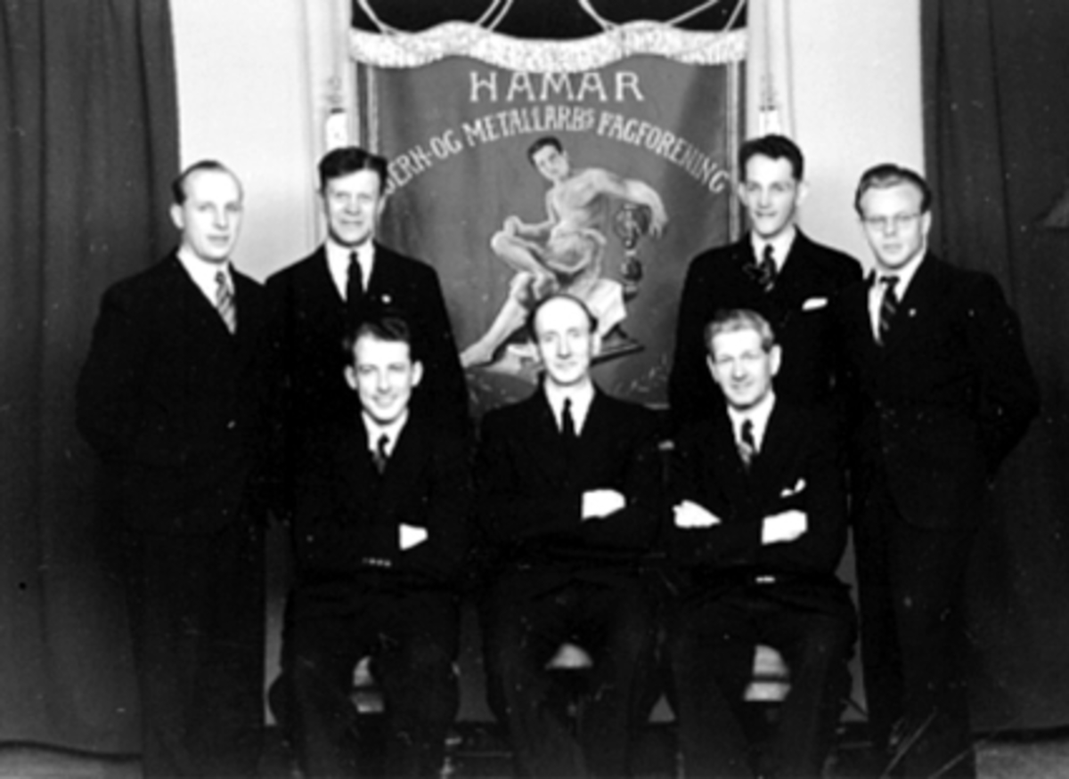 Anno Domkirkeodden, GRUPPE 7 MENN, HAMAR JERN OG METALLS STYRE, FANEForan fra v:Asbjørn O. Berg kasserer, Ole Olsen formann, Jens Hagen nestformann, Bak: Krf. Hein, Even Schøyen, Oskar Simensen, Oss Wold.