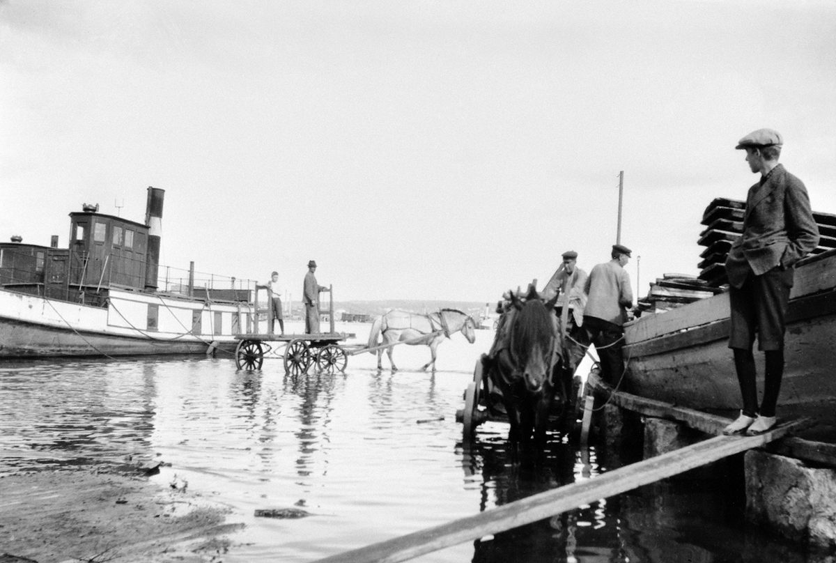 Anno Domkirkeodden, FLOM I MJØSA, 1927, 2 HESTER MED TRANSPORTVOGNER, 2 MJØSBÅTER, DEN ENE D. S BUNDEFJORD, HAMAR BRYGGE. Lasting av varer, hestetransport, hestekjøretøy.Båten til høyre i bildet er motorjakta Totenvik ex Svalen, opprinnelig seiljakt.