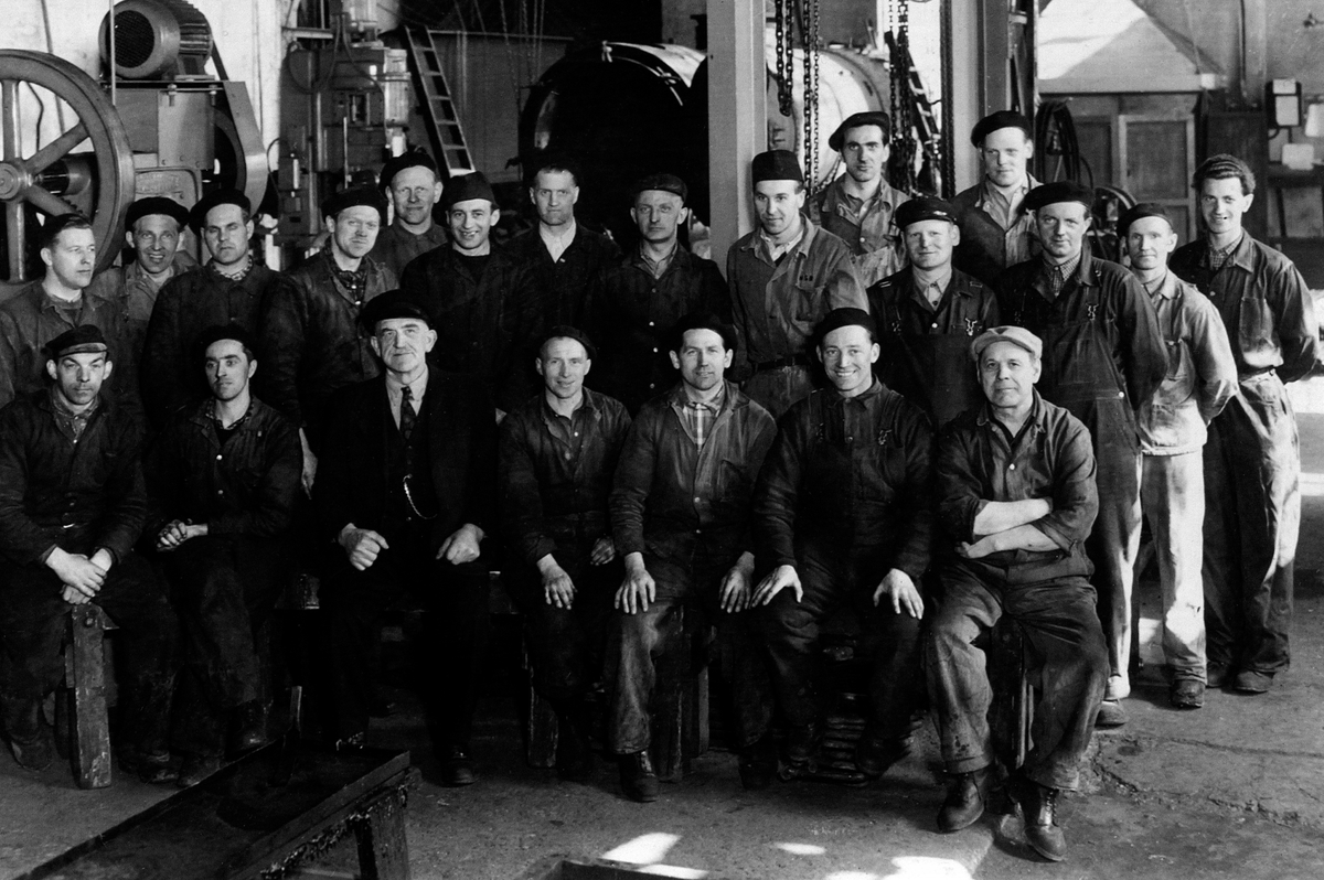 Anno Domkirkeodden, HAMAR JERNBANESTASJON. GRUPPE ARBEIDERE PÅ JERNBANEVERKSTEDET. CA 1950. 1 REKKE EIDOR KISE, OTTESTAD, MARIUS HOLM, LØTEN, TORVALD HOLM, OSLO, ODD WIIK, SARPSBORG, IVAR AASBREIN, RINGSAKER, JARLE LØKENHAGEN, ROMEDAL OG JØRGEN JØRGENSEN, HAMAR. BAKRE REKKE. ERLING KVARBERG, HJELUM, KRISTIAN GRINDAL, …