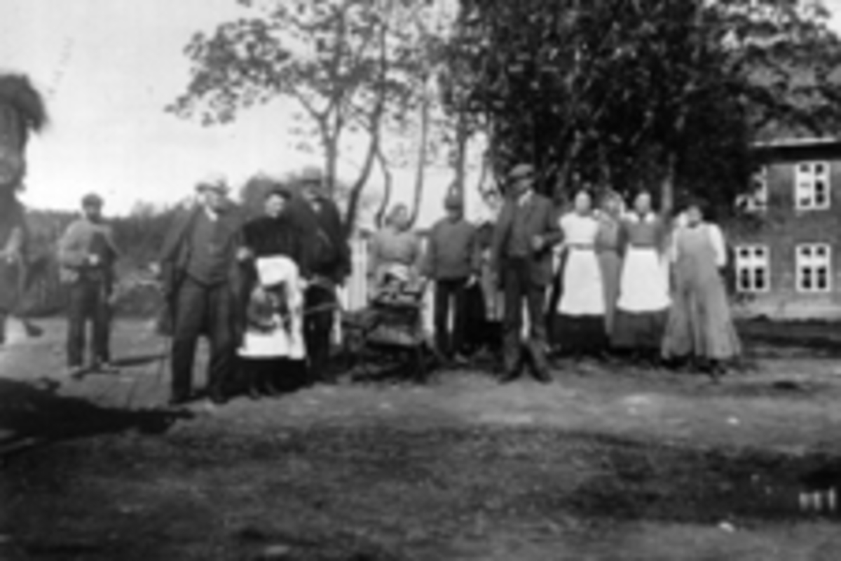 Anno Domkirkeodden, Gruppe voksne og barn på tunet på Mellem-Kise. Fra venstre er Per Rosenlund, lensmann Even A. Gjestvang, Arne O. Haugen, Christian Haugen, Caroline Sveiverud, Konrad Aaslund?, Lundstein, ukjent, ukjent, Beate Aaslund, ukjent, ukjent. Barna er stående Marie Haugen (Kongsrud), barnevogna Hans Haugen,…