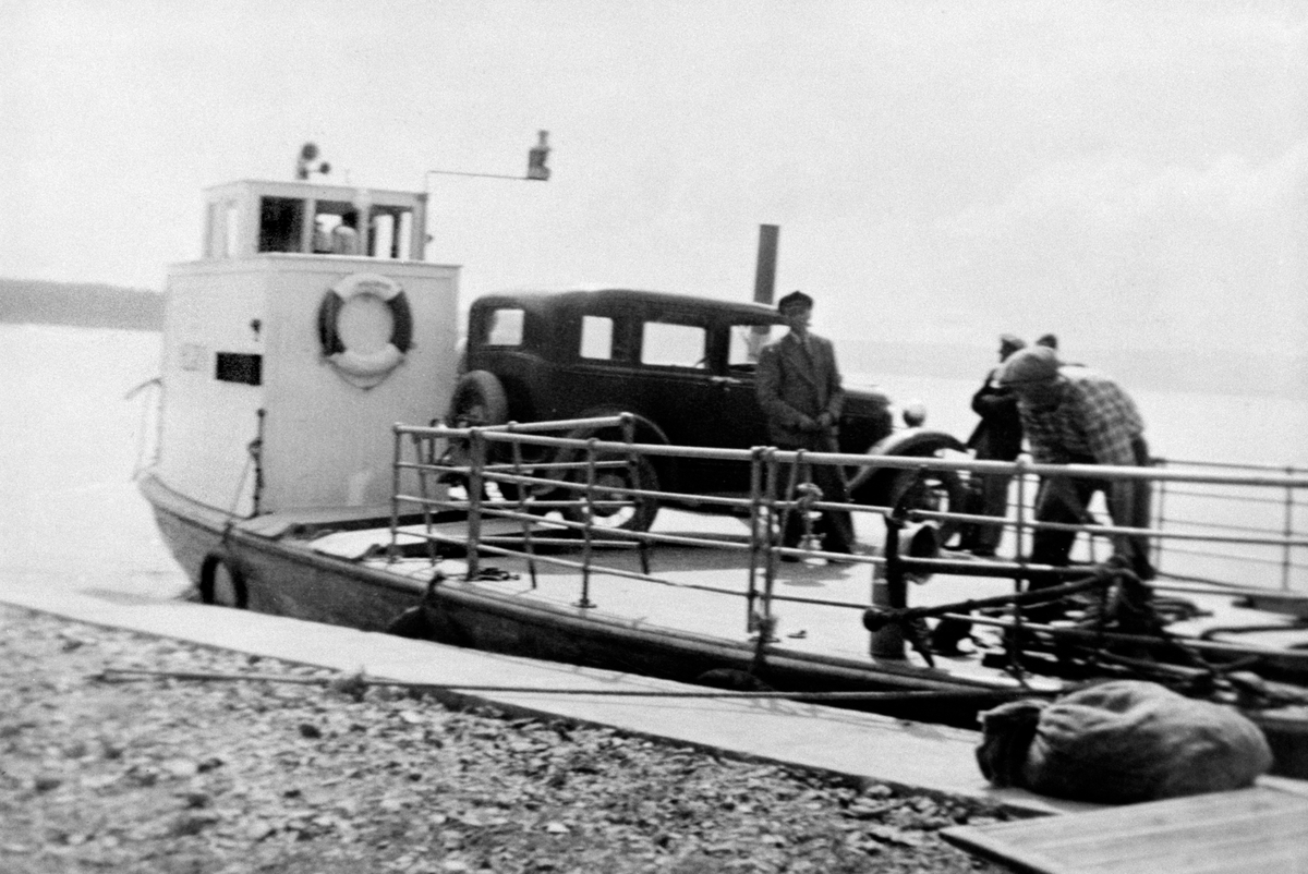 Anno Domkirkeodden, Mjøsbåten "Helgøya" ved Sundsbrygga på Helgøya. Liten bilferge med drosjen til Lars Presterud ombord. Bilen er en A-Ford 1930-31 med nummer D-530.