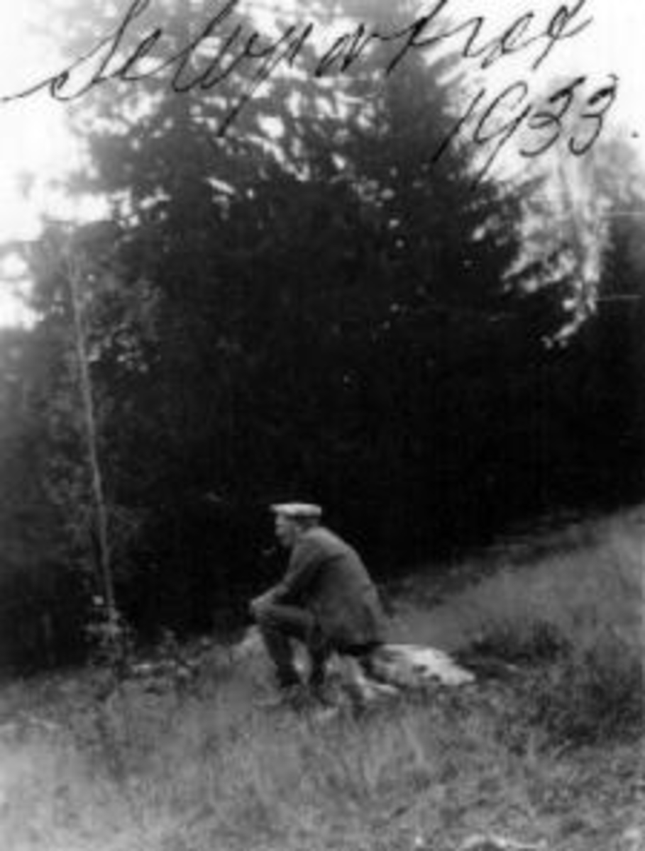 Anno Domkirkeodden, Selvportrett av fotograf Mikkel Sveinhaug. Sitter på en stein og røyker pipe.