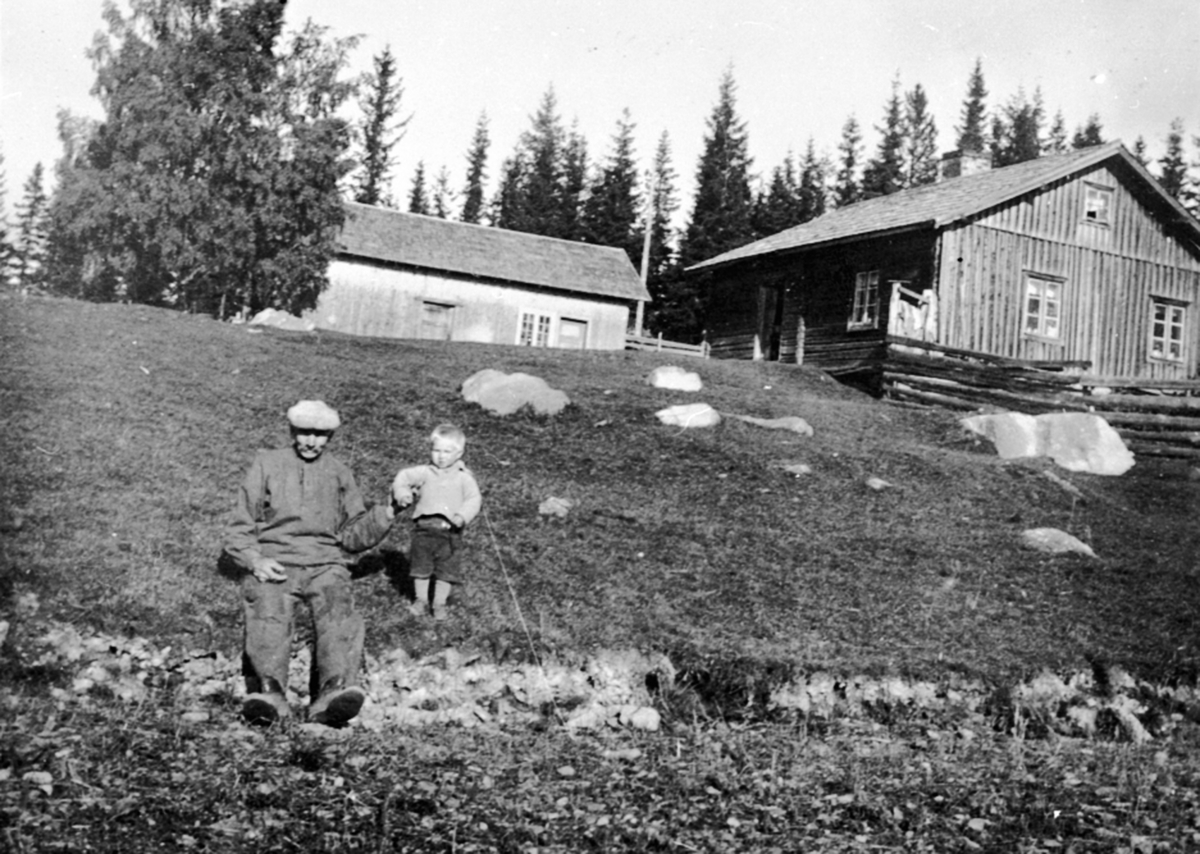 Anno Domkirkeodden, Mann og gutt nedenfor husa på Haugsveen søndre, Åsmarka, Ringsaker.