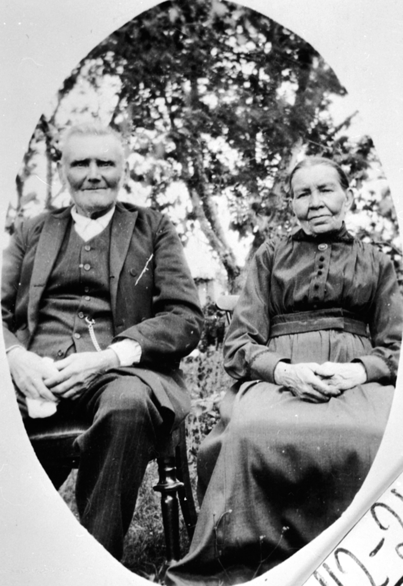 Anno Domkirkeodden, Ekteparet Johannes Akselsen og Marit Jensdatter sitter utenfor Sundby lille, Skredderbakken, Helgøya. Marit og Johannes kalte seg Aas Sundby da de døde. Marit,født Jensdatter Robole/Robøle i Øystre Slidre 29. mar 1852, død på Hamar 9. apr 1939. Johannes, født Axelsen, østre Toten 20. jan 1844, Død …