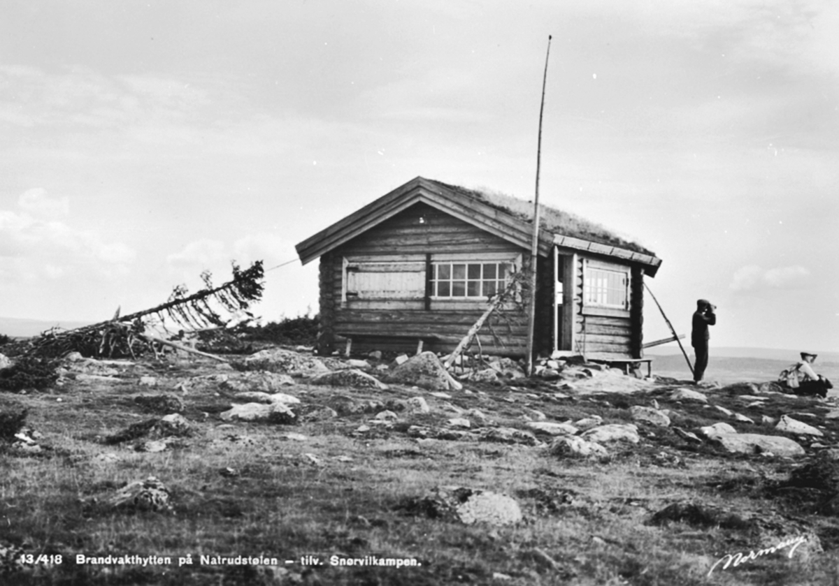 Anno Domkirkeodden, Eksteriør, brannvakthytta på Natrudstilen, bygd i 1930. Brannvakt Olaf Bekkelund med kikkert. Natrudstiltoppen, Ringsakerfjellet. Hadde telefonforbindelse med Brumundkampen og Knutberget i Stange. Hedmarksallmenningen eide alle vaktstasjonene. Ble ombygget i 1951-52