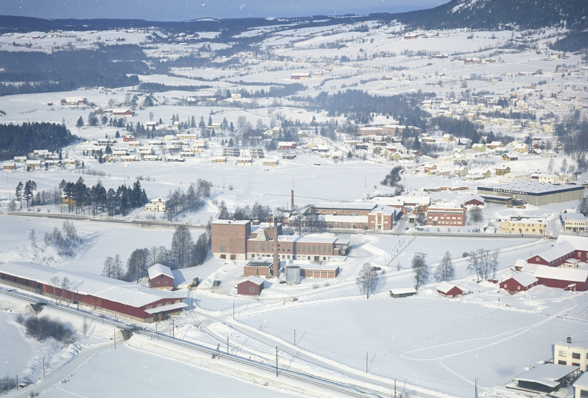 Widerøes Flyveselskap A/S, Flyfoto av Hedmark Tørrmelk, Nora Fabrikker A/S, Brumunddal. Bebyggelse ved Fagerlund skole. Vinter.