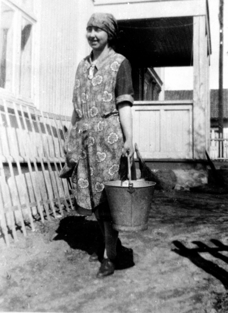 Anno Domkirkeodden, Lina Larsen med forkle, skaut og sinkbøtte henter vann. Brumunddal.