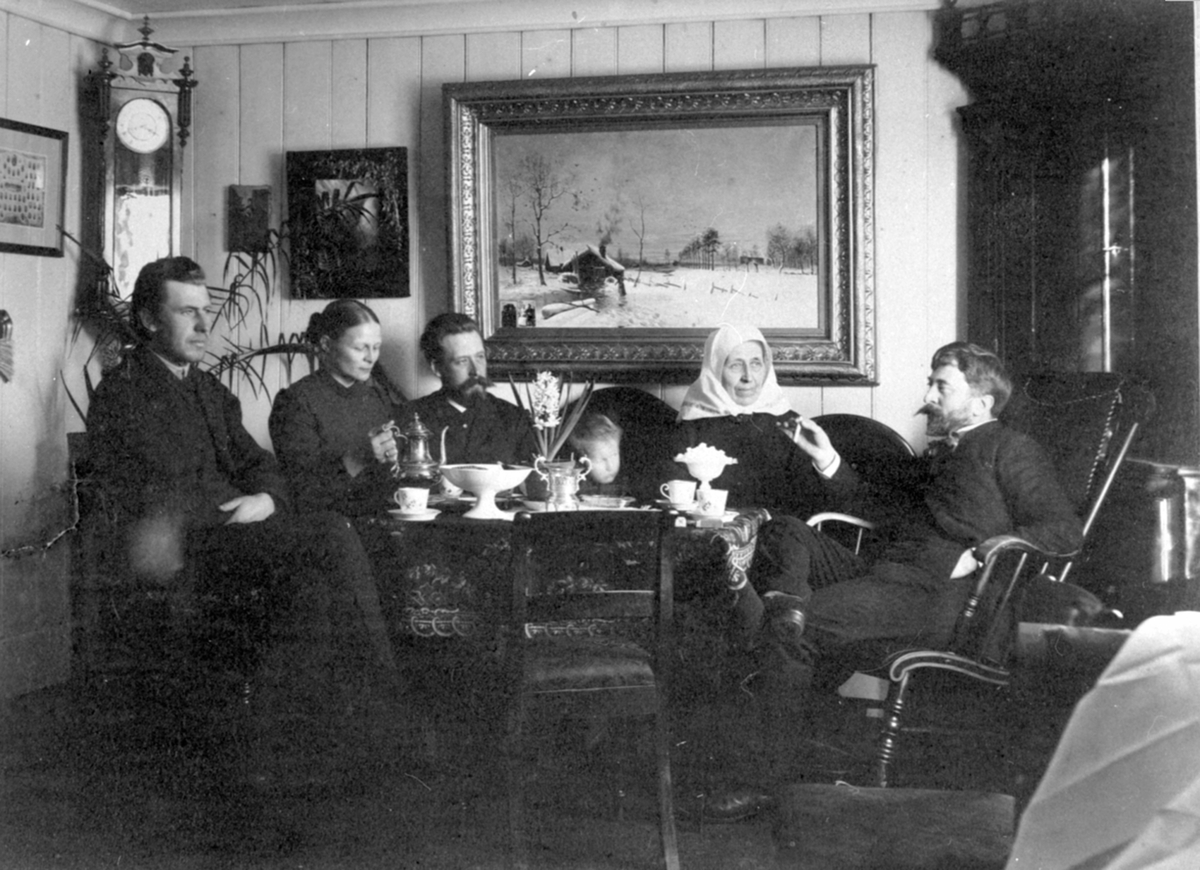 Anno Domkirkeodden, Interiør, Skoug gård, Brøttum, Ringsaker. Fra venstre er Johs Skoug, Berthe Skoug (f. Hundskjold), Erik Skoug, Jens Skoug f.1887, Lise Skoug (f. Saksum), kunstmaleren Eyolf Soot. Her på Skaug gård malte Soot "Velkommen" tre av personene på bildet sto modell.