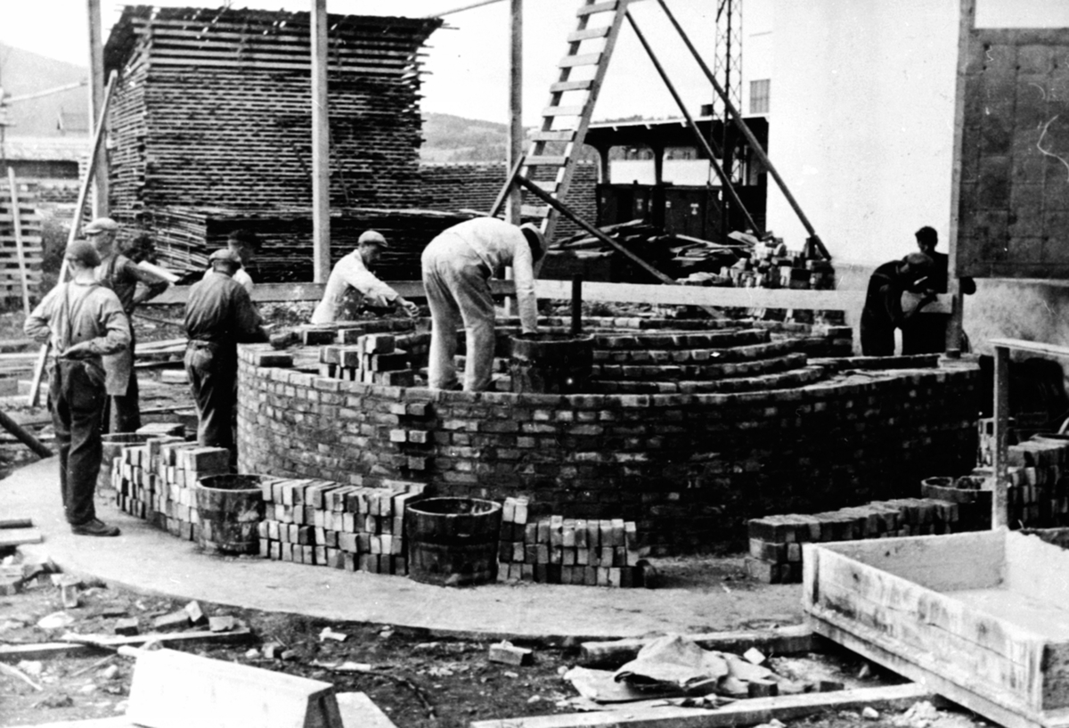 Anno Domkirkeodden, Oppmuring av fabrikkpipe hos Berger Langmoen A/S, Brumunddal. "Langmopipa" Murere Amund Sletten f. 1880 og sønnen Olav Sletten f. 1915 fra Fåberg . De øvrige ukjente , håndlangere, var fra anleggsgjengen ved Langmoen.