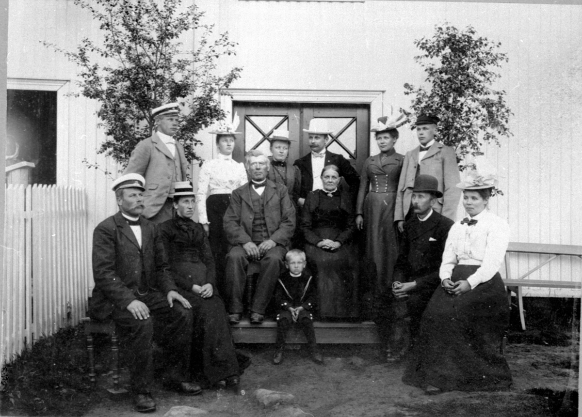 Anno Domkirkeodden, Familien Johs Schjerpen, forpakter på Dusgard, Ring, Ringsaker. Foran fra venstre er Ole Schjerpen, Kristine Schjerpen, Johs. Schjerpen, Anne Schjerpen, Harald Grim og Oridia f. Schjerpen. I midten Karl Grim. Bak fra venstre er Petter Schjerpen, ukjent, Marie Kløvenberg f. Schjerpen, Erik Schjerpen…