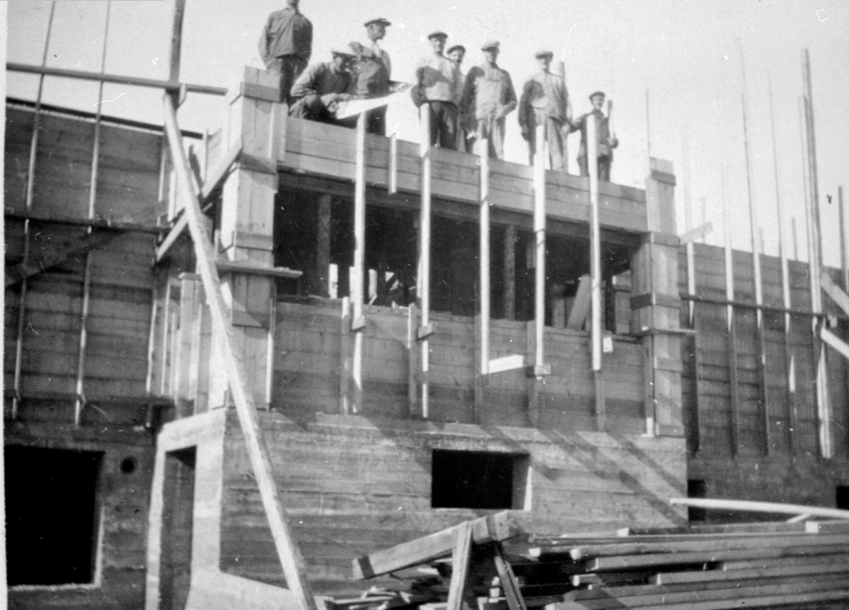 Anno Domkirkeodden, Bygging av Promenadekafeen, senere Hogstadbygget i Furnesvegen, Brumunddal. Gruppe menn arbeider med forskaling. Promenadekafeen var Brumunddals første bygg i betong og ble satt opp i 1930. "Promenaden" het den på folkemunne.