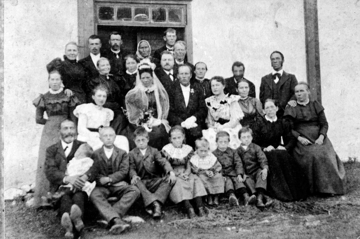 Anno Domkirkeodden, Brudepar og stor gruppe bryllupsgjester på Fjell gård, Helgøya. Brudeparet er Otlie Torsdatter (1855-1927) og Kristian Bratberg (1860-1932). Foran hovedbygningen på Fjell. Foran er noen av barne på Nedre Maurud.