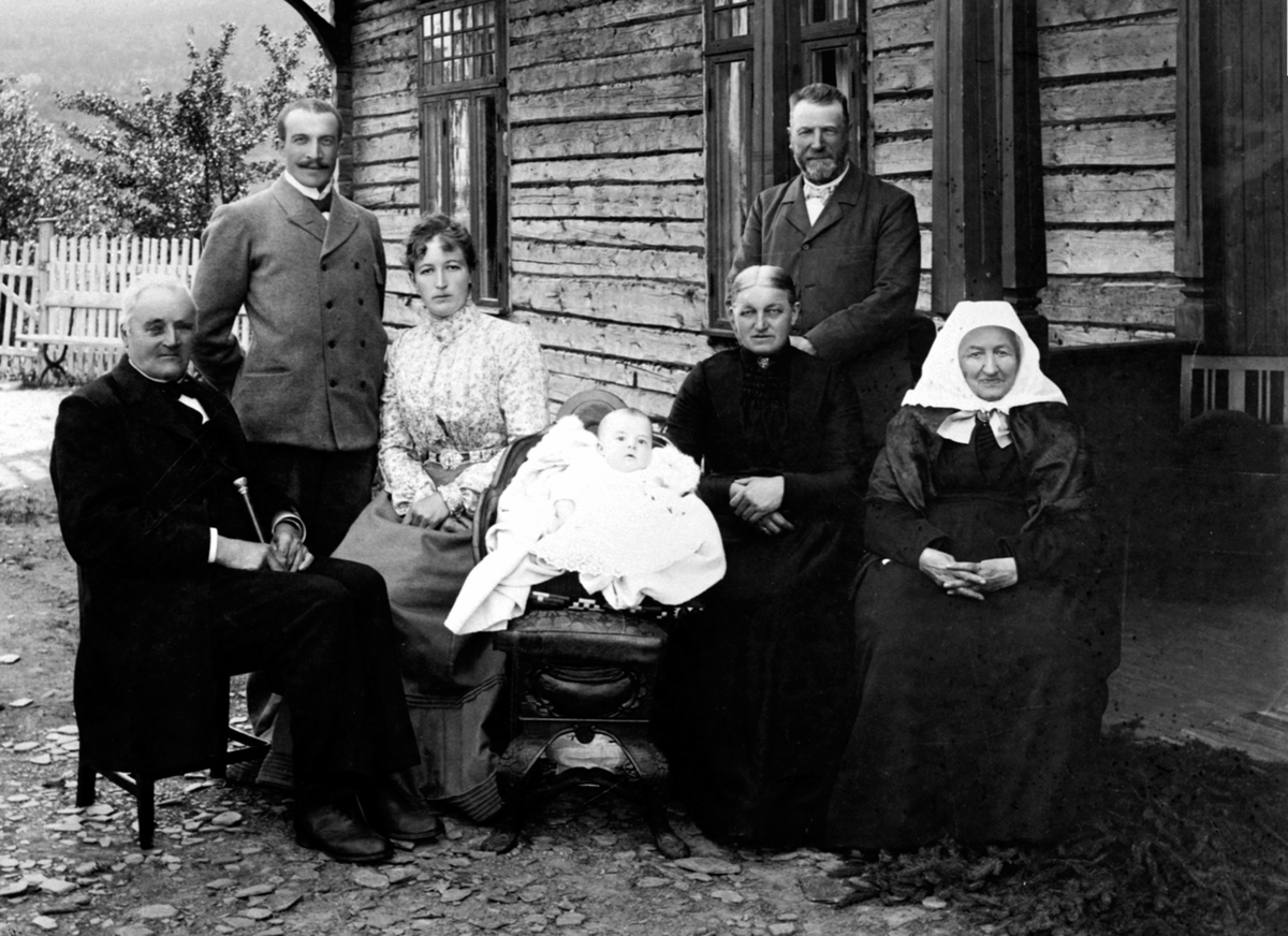 Anno Domkirkeodden, Barnedåp, Narud gård, Veldre, Ringsaker. Fra venstre er Johannes Narud f.1812, Birger Bjerke, Marthe Bjerke f. Narud, dåpsbarnet Lars Bjerke Narud, Louise Narud f. Flisaker 1851, Lars Narud f.1845, Berthe Narud f. Bjørnerud 1823.