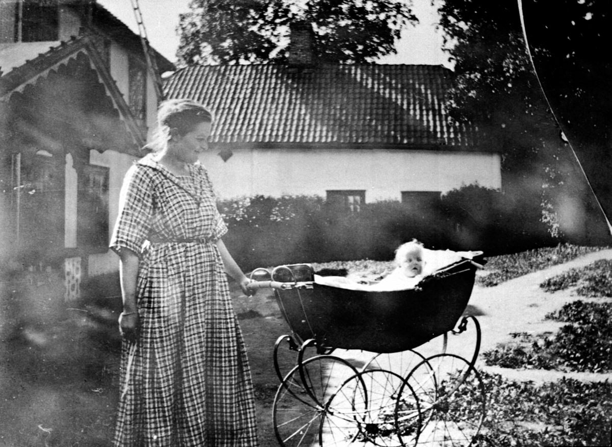 Anno Domkirkeodden, Dame med baby i barnevogn foran inngangspartiet til hovebygningen på Hovelsrud, Helgøya.