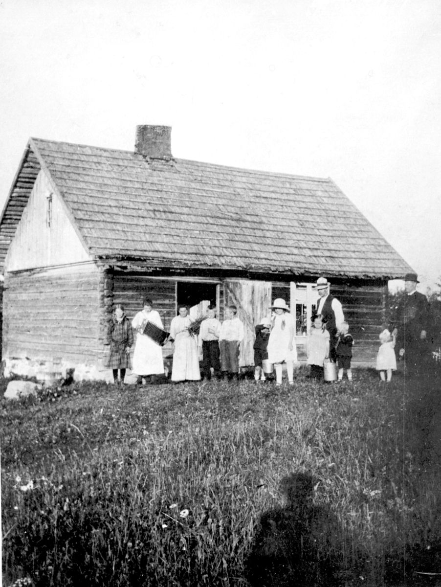 Anno Domkirkeodden, Husmannsplassen Svartbækken/Høystad, Helgøya. Stor gruppe barn og voksne foran huset.