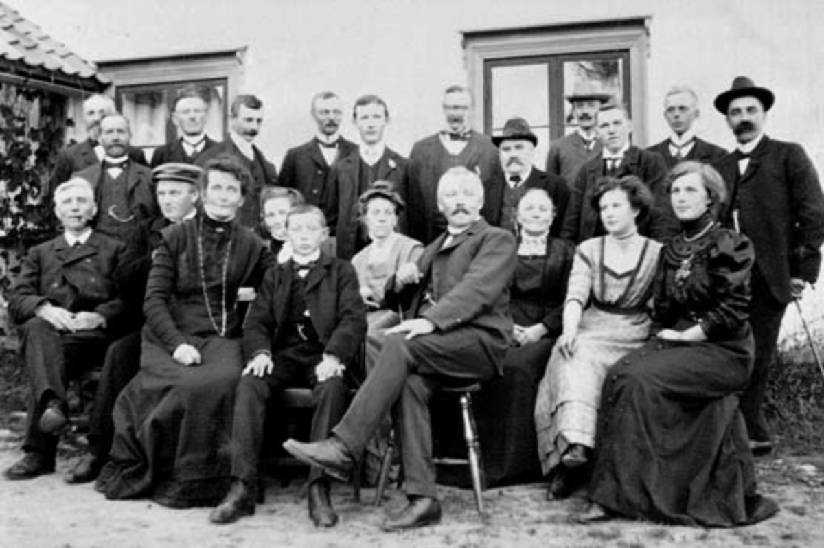 Anno Domkirkeodden, Stor gruppe foran hus på Ousdal nordre, Nes, Hedmark. Martin Finborud med hatt og frakk i midten bak.