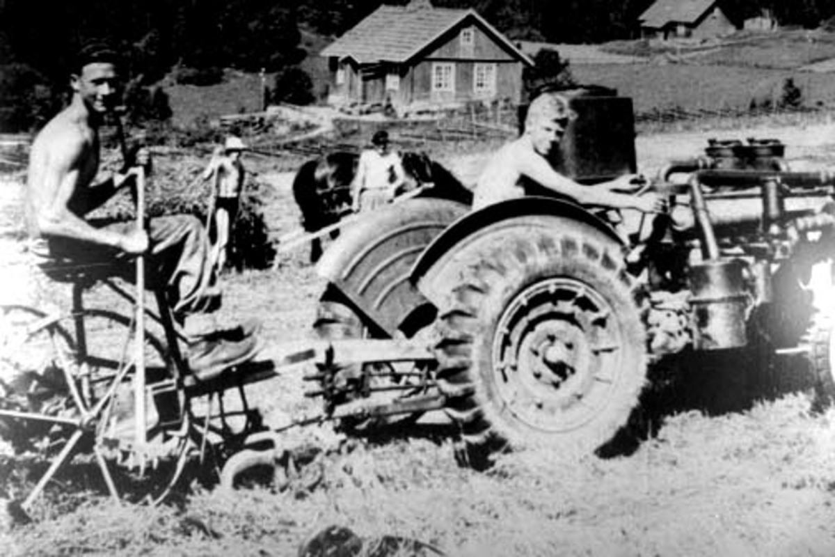 Anno Domkirkeodden, Slåttonn på Aske nordre, Nes, Hedmark. Ferguson traktor 1938 modell med gummihjul. Generator og slåmaskin. På traktoren sitter Ole Bråstad f.1929, på slåmaskina Svein Myrset, ved hesten Helge Hammersborg og ved høylasset Per Hjelt. I bakgrunnen er husmannsplassene Askesveen og til høyre Skredderbak…