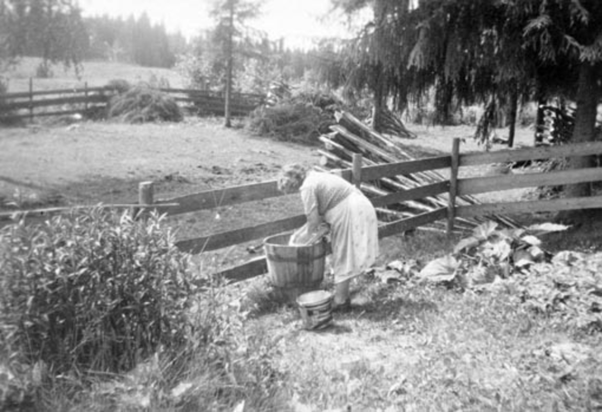 Anno Domkirkeodden, Marie Olsen (1897-1981) vasker klær utendørs med trestamp og vaskebrett. Nerby, Stavsjø.