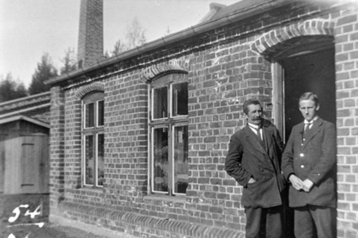 Anno Domkirkeodden, Globus maskinfabrikk, Brumunddal, 2 menn foran fabrikklokalet.
