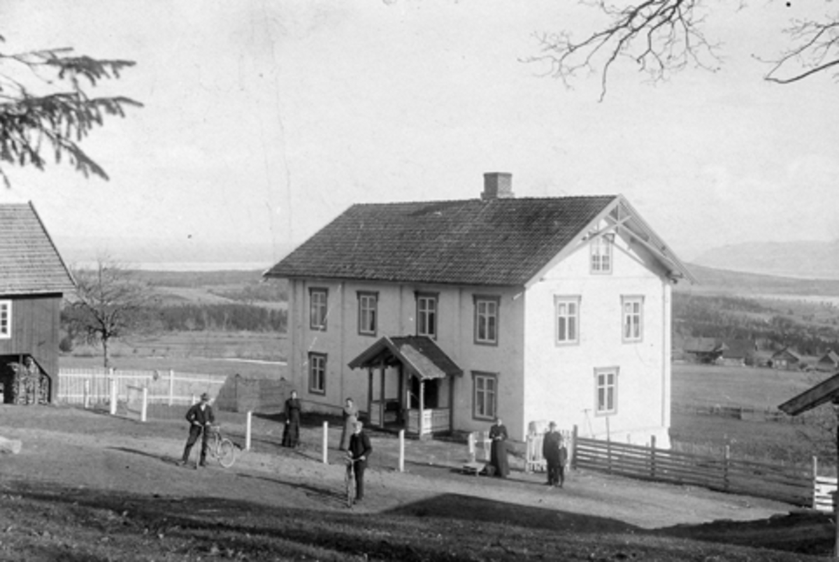 Anno Domkirkeodden, Eksteriør fra Berg øvre, Nes, Hedmark. Nedre Hove i bakgrunnen. Den gamle hovedbygningen var bygd omkring 1822. Familie samlet på tunet. Foran med sykler er fra venstre Nils (1887-1923) og Øvert (1893-1973). Jentene bak er fra venstre Marie (1886-1947) og Martha f.1890. På hjørnet er Milla (1862-19…