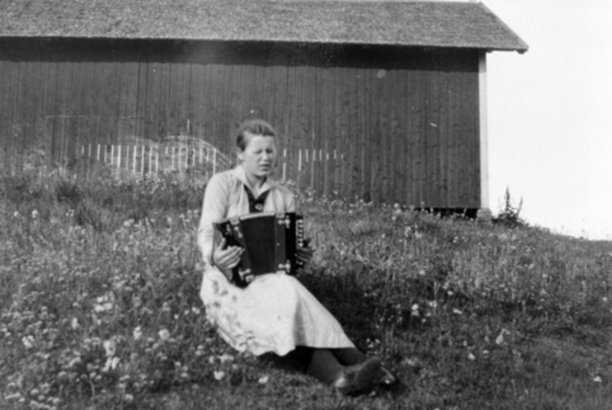 Anno Domkirkeodden, Marie Lier sitter i gresset med toraders trekkspill. År 1919.