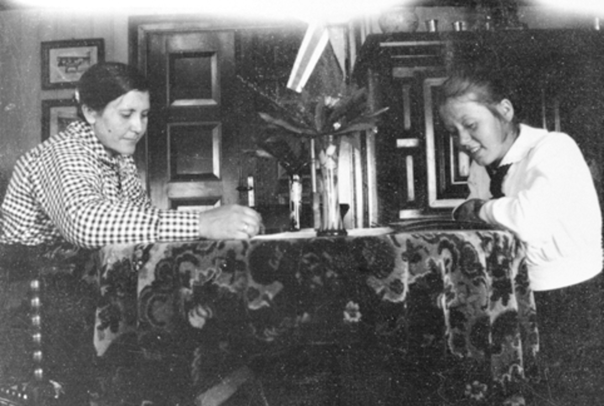 Anno Domkirkeodden, Interiør, storstua på Mørkved store, Furnes. Dina og Marie Lier ser i album. Bak til venstre står et stort hollandsk skap.