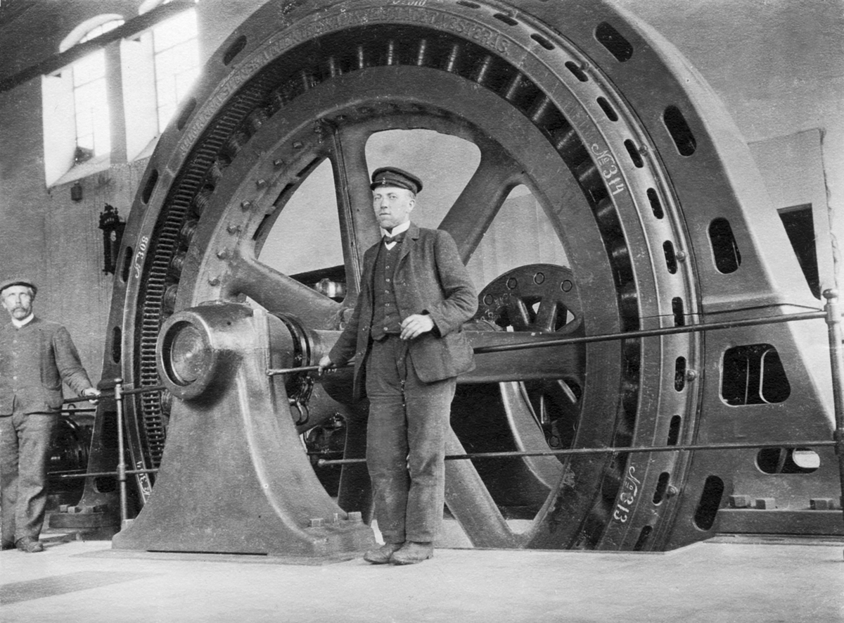 Anno Domkirkeodden, Moelven Elektrisitetsverk, bygget for å forsyne Moelven Cellulosefabrikk med strøm. 2 ukjente menn ved turbin. Ca. 1908-10.