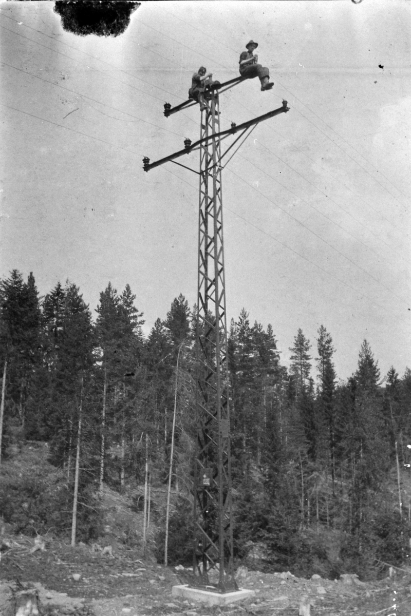 Anno Domkirkeodden, 2 montører fra Ringsaker og Nes Kraftanlegg monterer kraftledning i toppen av jernmast. Ca. 1920-21.