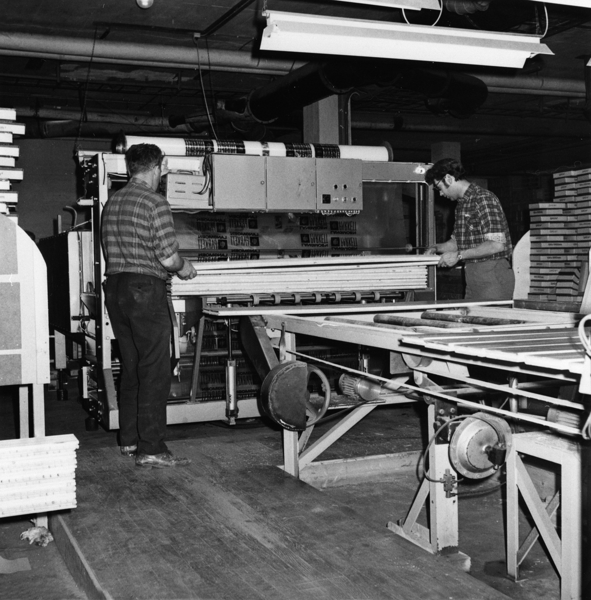 Anno Domkirkeodden, Berger Langmoen A/S, Brumunddal. Interiør, parkettfabrikken. Innkjøring av ny fabrikk, 2 arbeidere mater maskin. Produksjonen kom igang i september 1963.
