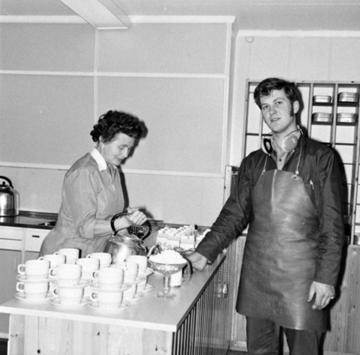 Anno Domkirkeodden, Berger Langmoen A/S, Brumunddal. Kaffeservering i kantina. Else Engen serverer Odd Elvsvebakken kaffe. Kantina i EBW.Wallboardfabrikken.