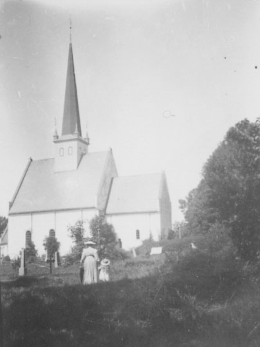Normann Helger, EKSTERIØR: STANGE KIRKE, MOR MED DATTER I FORGRUNNEN. , HATTER, PARAPLY,