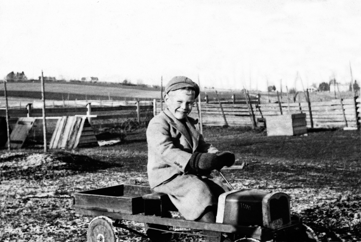 Anno Domkirkeodden, ODD KJELL SKJEGSTAD, 6 ÅR, LEKEBIL, TRÅKKEBIL, BARNELEKE, UTHUS GARD, STANGE, OKTOBER 1941. FAREN A, SKJEGSTAD HADDE BILDET OVER SENGA SI DA HAN SATT PÅ GRINI UNDER KRIGEN, MEN DET BLE FORBUDT. HAN GJEMTE DET OG OPPBEVARTE DET ILLEGALT. SE ÅRBOKA " GAMMALT FRA STANGE OG ROMEDAL"2004 SIDE 22.
