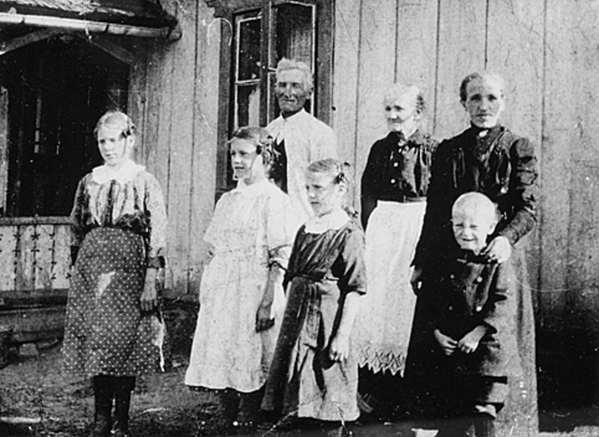 Anno Domkirkeodden, NORDRE VOLLA, HUSMANNSPLASS UNDER STANGE PRESTEGARD, GRUPPE 7 HUSMANNSFAMILIE. BAK. F. V. HUSMANN JENS JENSEN OG HANS KONE HELENE LARSDATTER OG DATTER TRINE JENSDATTER G. KRISTIANSEN. FORAN F. V HELGA, SIGNE, KIRSTEN OG KRISTAN, CA. 1918.