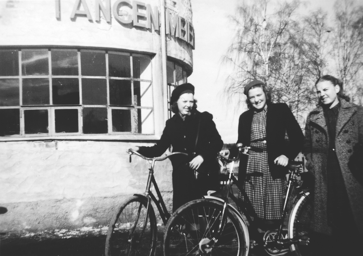 Ukjent, F. v Astrid Nyhus, Gerd Lise Alm og Gerd Strand utenfor Tangen Meieri.. De var elever ved Tangen Arbeidsskole. Sykler. Flere opplysninger se boka "Handelssteder i Stange" skrevet av Jan Arne Berg, utgitt av Stange Historielag 2012