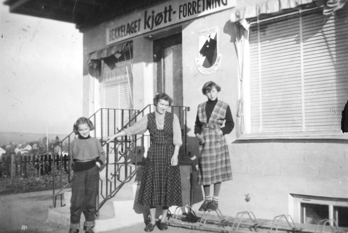 Ukjent, Bekkelaget kjøttforretning i 1955, eksteriør. Innehaver Einar Tønseth. T. v. utenfor butikken Laila Bratlie, Agnes Bratlie og Marit Bratlie Flere opplysninger se boka "Handelssteder i Stange" skrevet av Jan Arne Berg, utgitt av Stange Historielag 2012