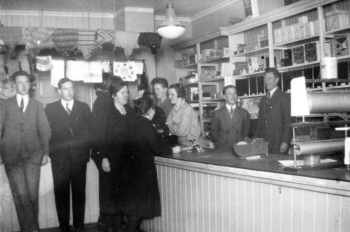 Ukjent, Stange kooperative selskap, butikken i Sørholtbygningen i Stange sentrum. F. v. foran disken Ottar Kristiansen, Magnus dahl, Alis Olsen, og Anne Sørli. Bak f. v. Knut Fjæstad, Helene Nordli, Kåre Rønning og Alfred A. Dahl. Butikk, interiør. Vareopptelling 1928. Gr. nr. 93-29. Flere opplysninger se …