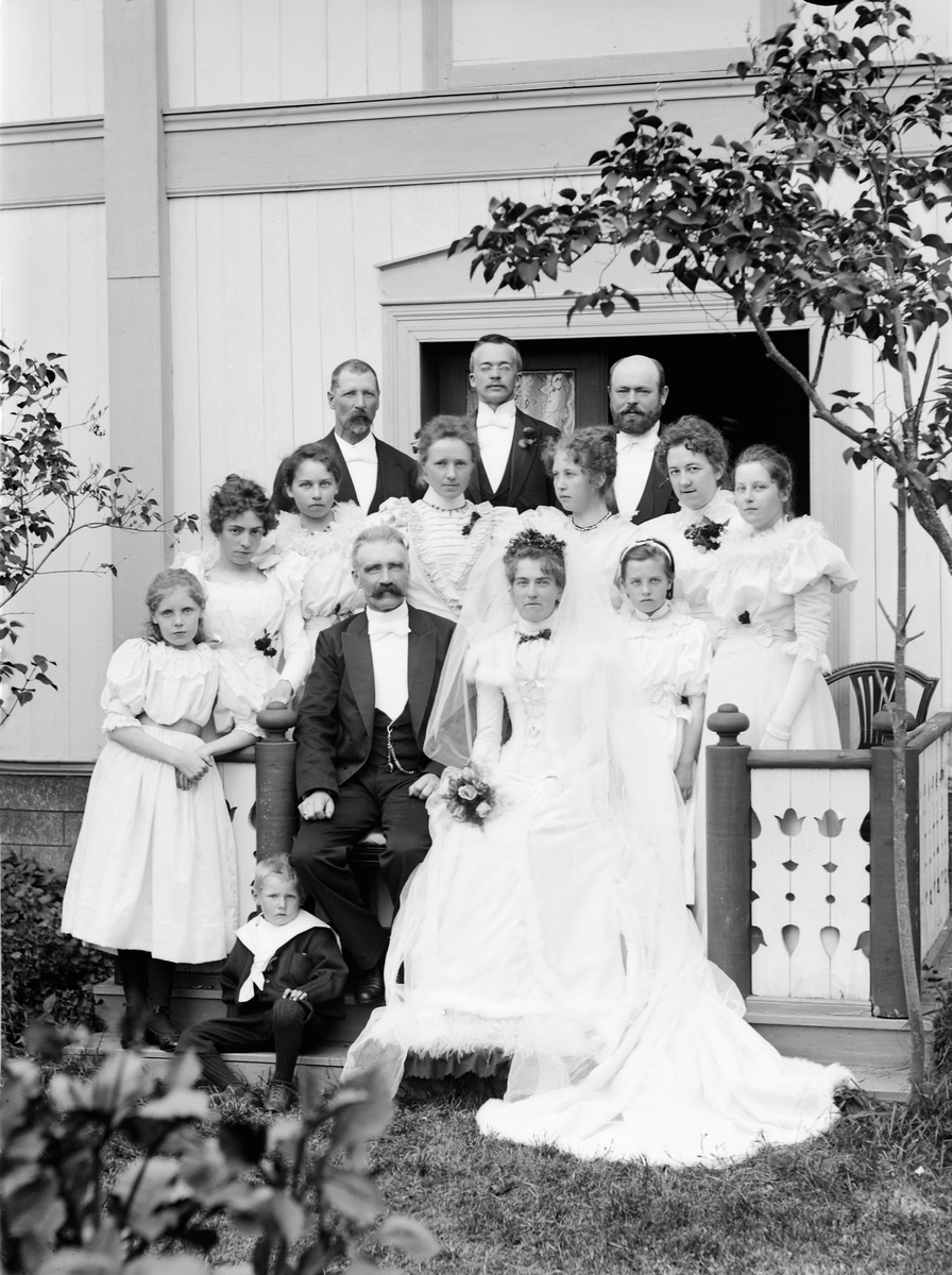 Martin Finborud, Brudepar for huset på Svennerud, Helgøya. Brudeparet er Andreas Botolfsen Trønnes (1850-1920) og Hanna Antonsdatter Svenkerud (1872-1930). Gutten ved brudgommens føtter er trolig minstegutten Halvor (1892-1975) fra første ekteskap.