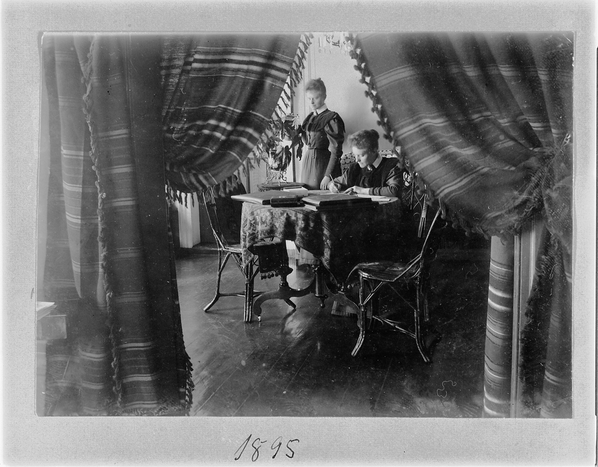 Johan Albert Steen, Stueinteriør hos familien Steen, 2 damer, møbler.