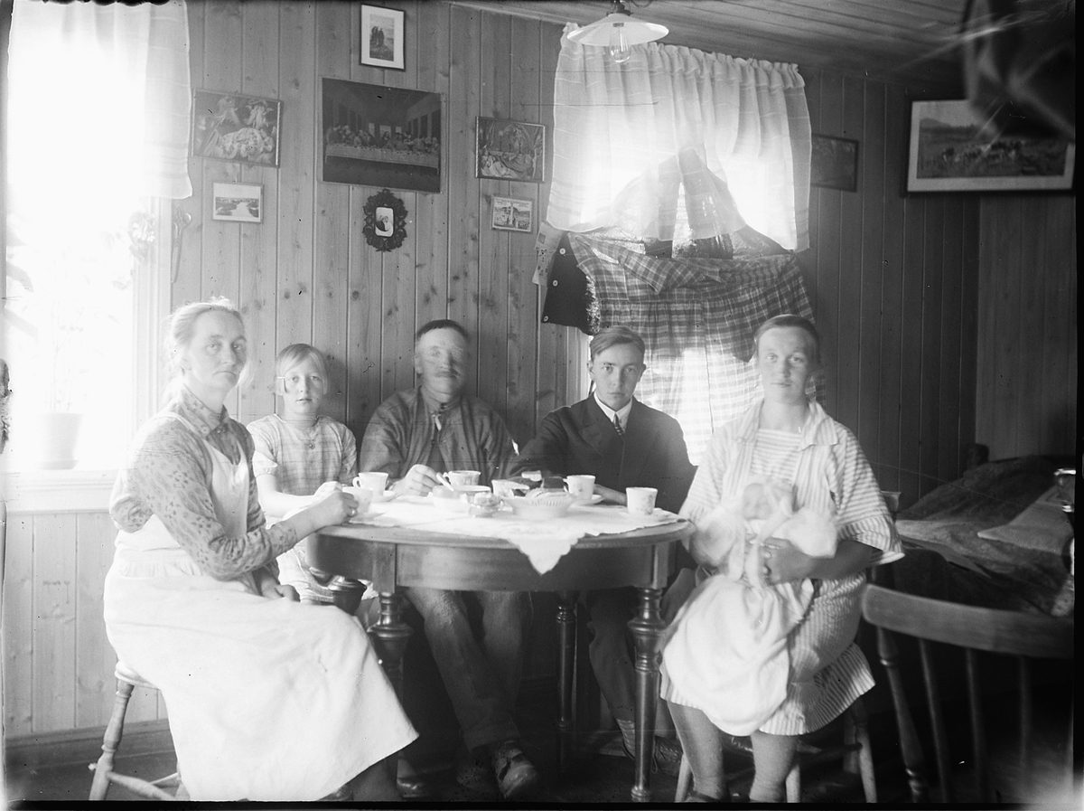 Ole M Martinsen, Ukjent gruppe, familie, drikker kaffe. Kvinne med baby på fanget. Interiør, stue.