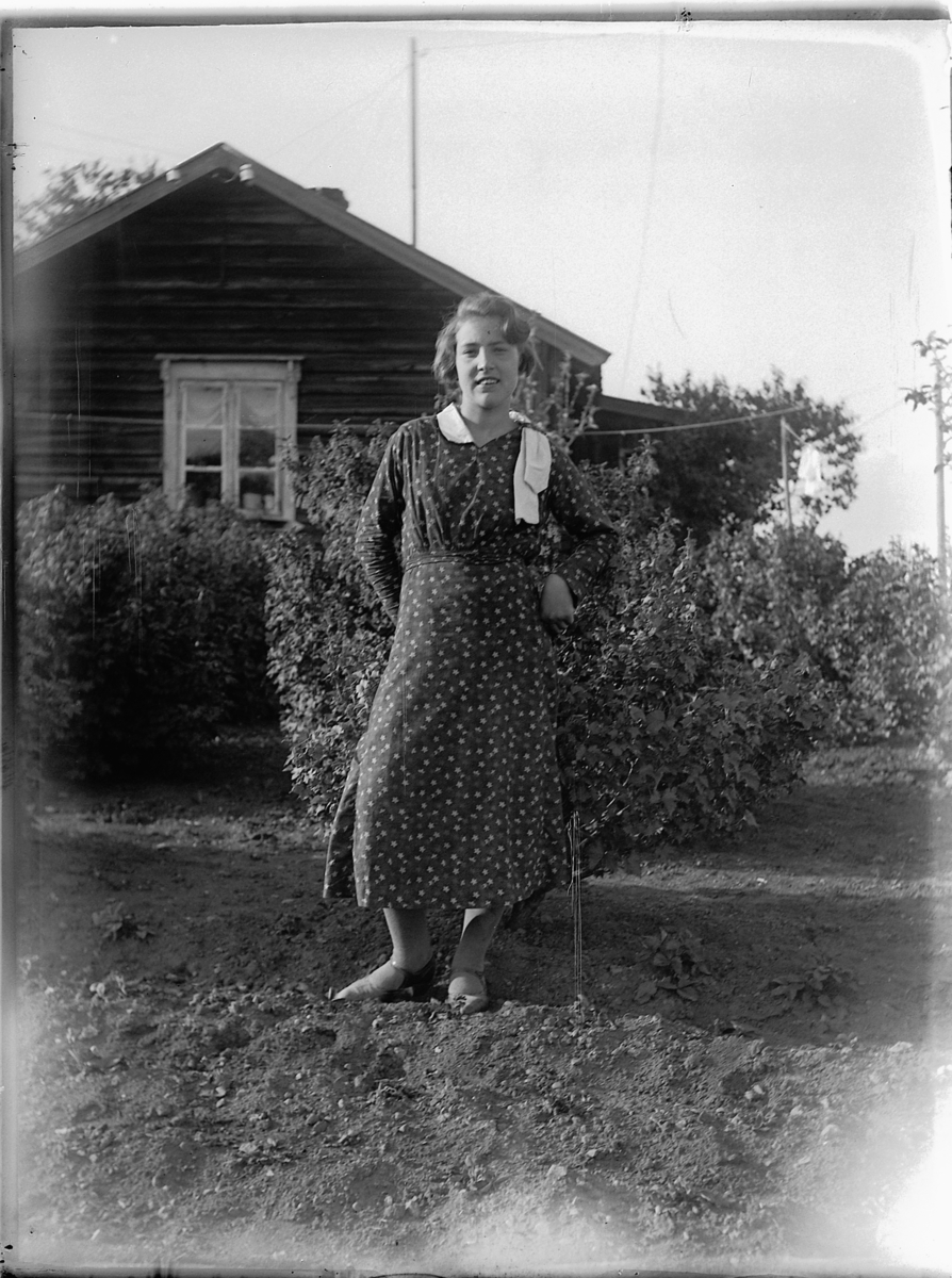 Ole M Martinsen, Ukjent kvinne i hagen ved et hus.