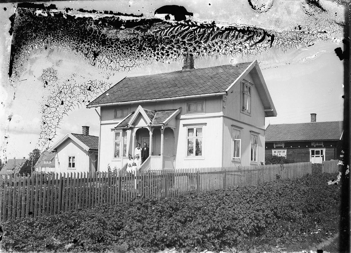 Oscar Løberg, VILLA LINDHØY, GUNNARS GATE 22, Hamar, BYGD 1914, PÅ VERANDAEN FAMILIEN HANSEN SOM EIDE VILLAEN. TH. ODVAR HOELS HUS HEGGEN FRA 1913, TV. TO VILLAER TILH. NORDVIGEN BRUK, LENGST TV. BODDE DISPONENT ARNESEN, OG VED SIDA AV KONTORSJEF HORNE.