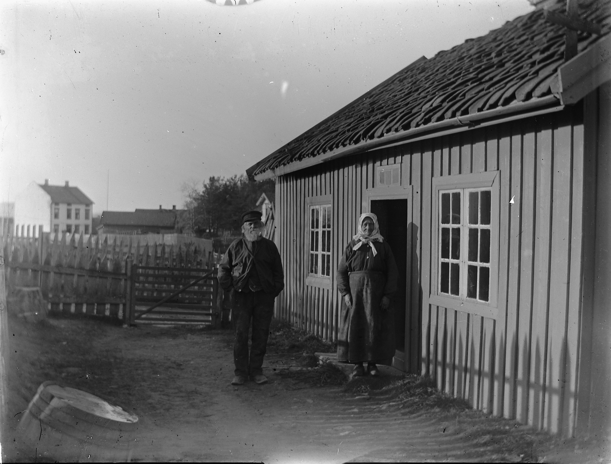 Johs. (Johannes) Johannessen, Ukjent eldre mann og kvinne ved inngangsdør til et hus.