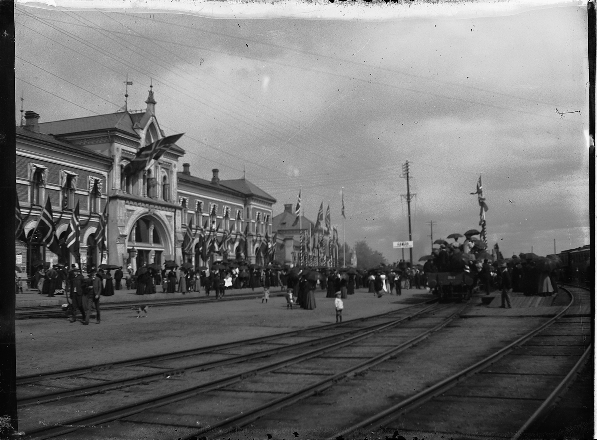 Johs. (Johannes) Johannessen, HAMAR JERNBANESTASJON, PYNTET MED FLAGG under kroningsreisen, signingsferden til Kong Haakon og Dronning Maud.