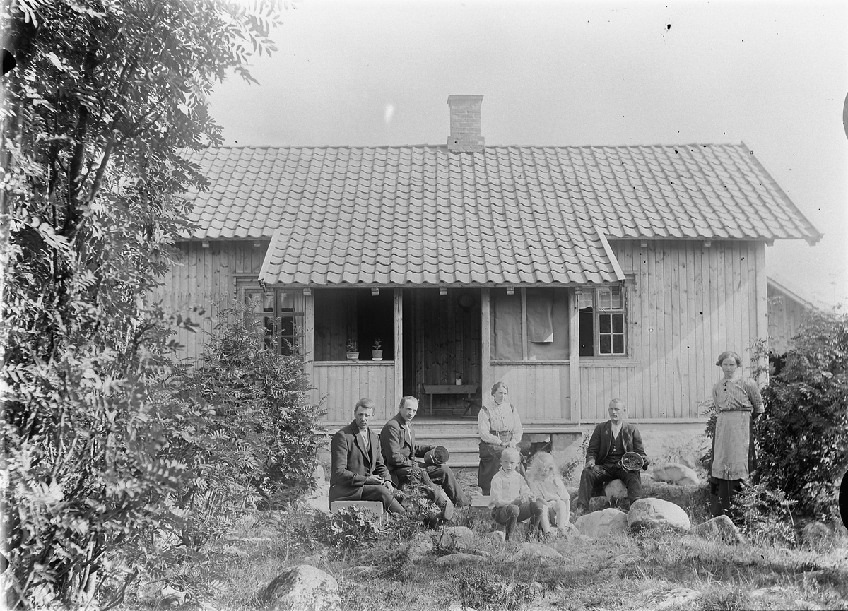 Mina Skraastad, Kluksetra, tilh. Skraastad Øvre, Vang Almenning. 7 ukjente barn, voksne foran seterhus/hytte. Vangsåsen. Tre menn, to kvinner, og to barn foran et hus.
