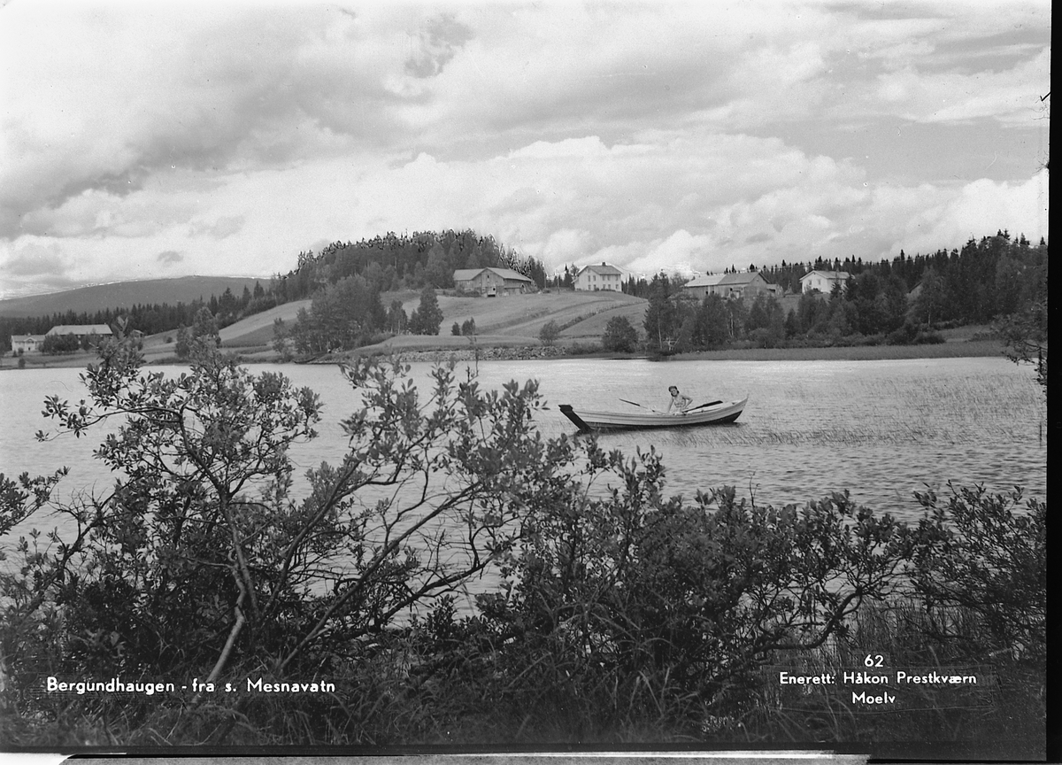 Håkon Prestkværn, Postkort. Fra s. Mesnavatn. Foto Håkon Prestkværn, Moelv. No. 62. Sør-Mesna. Ukjent kvinne i robåt(åfløy). TIL VENSTRE: HAUG GÅRD, ØVRE BERGUNDHAUGEN OG SØNDRE BERGUNDHAUGEN VED SØR-MESNAVANNET i Ringsaker,