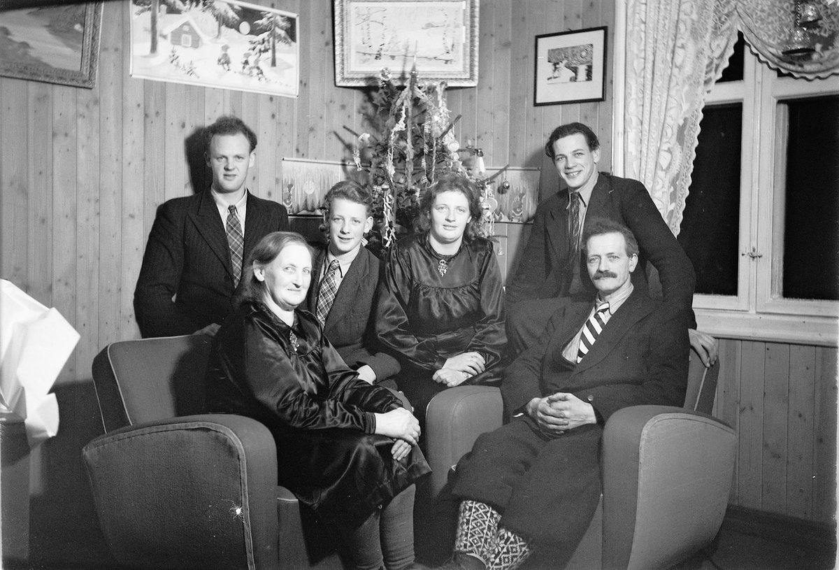 Håkon Prestkværn, Interiør, stue. Sparemøte, Syvertsen. Ukjent gruppe kvinner og menn foran et juletre.