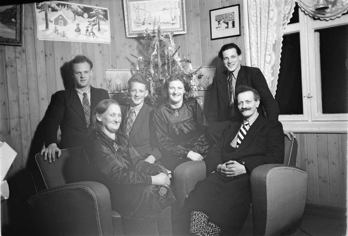 Håkon Prestkværn, Interiør, stue. Sparemøte, Syvertsen. Ukjent gruppe kvinner og menn foran et juletre.