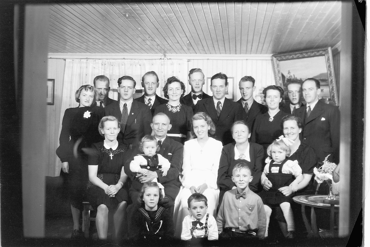 Håkon Prestkværn, Interiør, stue, konfirmasjon, Sveum. Konfirmanten med gjester. Stående fra venstre: Agnes Larsen, Laurits Bekkeli, Gunvald Sveum, Johannes J. Sveum, Signe Gjørslie, Konrad Mæhlum, Lars A. Gjørslie, Sverre Sveum, Paula Haug, Rolf Sveum og Johannes Haug. Sittende fra venstre: Bergljot Bekkeli, Johann…