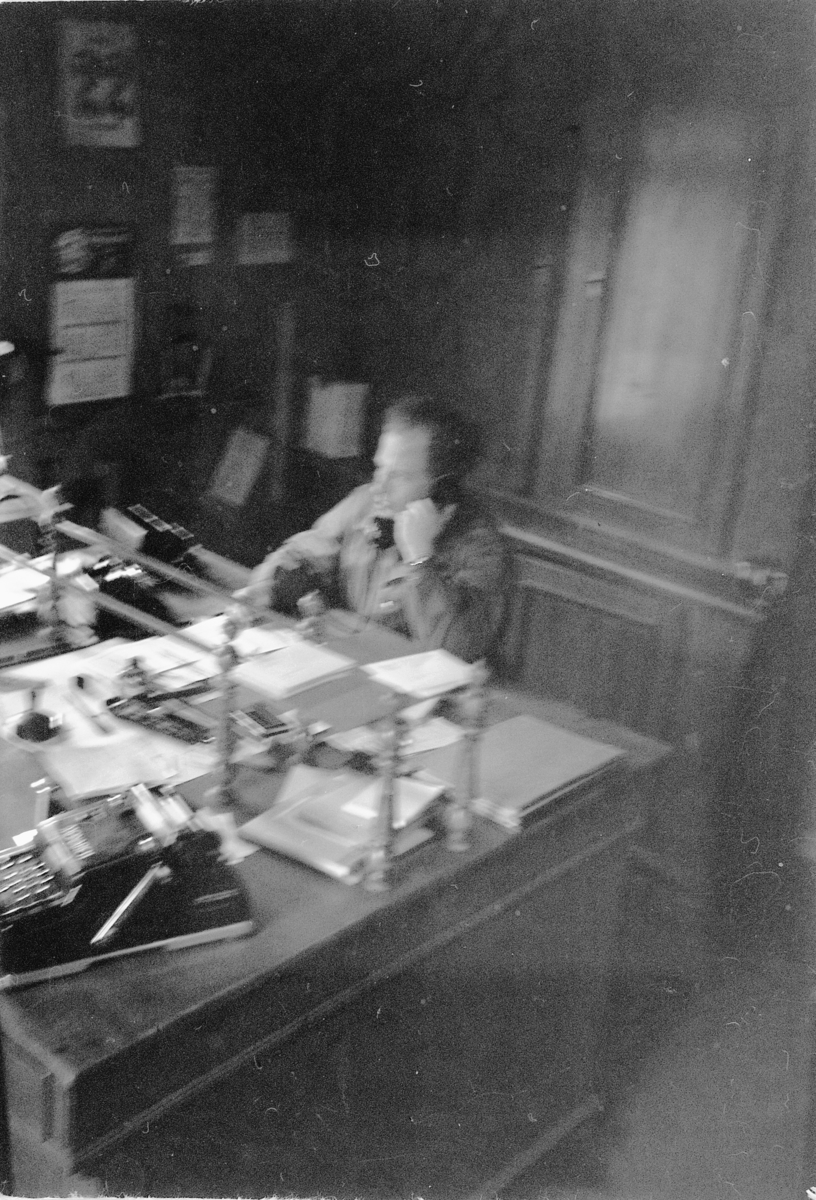 Håkon Prestkværn, STRAND BRÆNDERI i Ringsaker, BRENNERI. Mann i telefonen ved kontorpult.