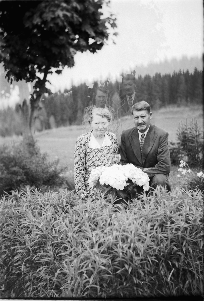 Håkon Prestkværn, Ukjent kvinne og mann med blomster i en hage med jorde og skog i bakgrunnen.